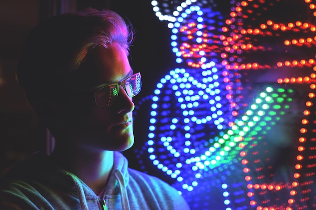 close-up of young man looking at illuminated lighting equipment in darkroom