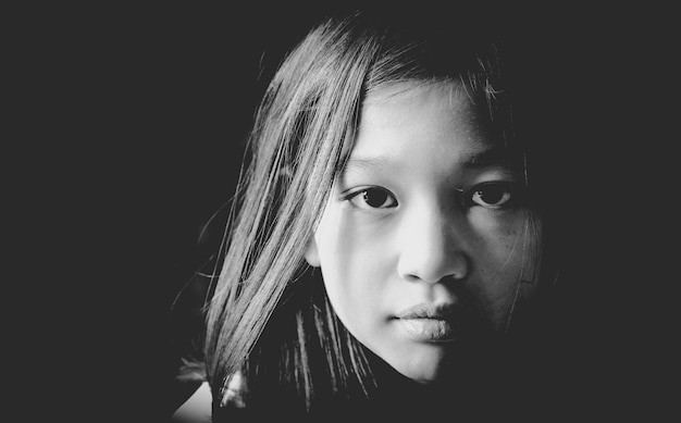 Close-up portrait of girl against black background