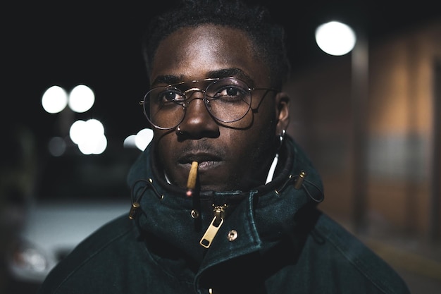 close-up portrait of young man smoking marijuana joint at night