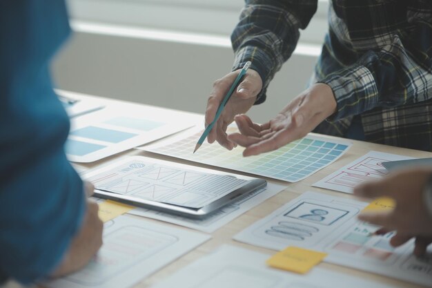 close up ux developer and ui designer brainstorming about mobile app interface wireframe design on table with customer breif and color code at modern officecreative digital development agency