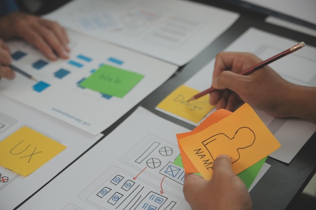 close up ux developer and ui designer brainstorming about mobile app interface wireframe design on table with customer breif and color code at modern officecreative digital development agency