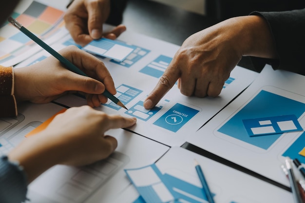 close up ux developer and ui designer brainstorming about mobile app interface wireframe design on table with customer breif and color code at modern officecreative digital development agency