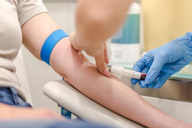 Closeup of doctor taking blood sample from patients arm in hospital for medical testing