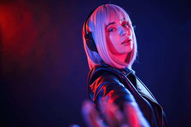 conception of music listening in headphones woman with white hair is in studio with neon colors