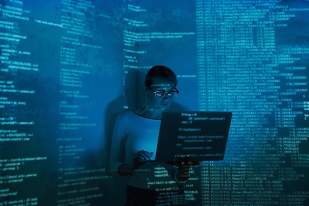 Confident young woman using computer against dark background