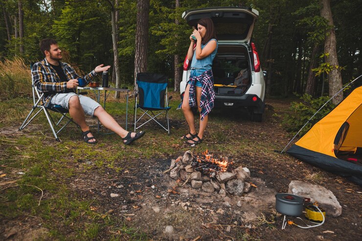 Fotografie couple sitting in portable chairs drinking tea talking camping summer activities