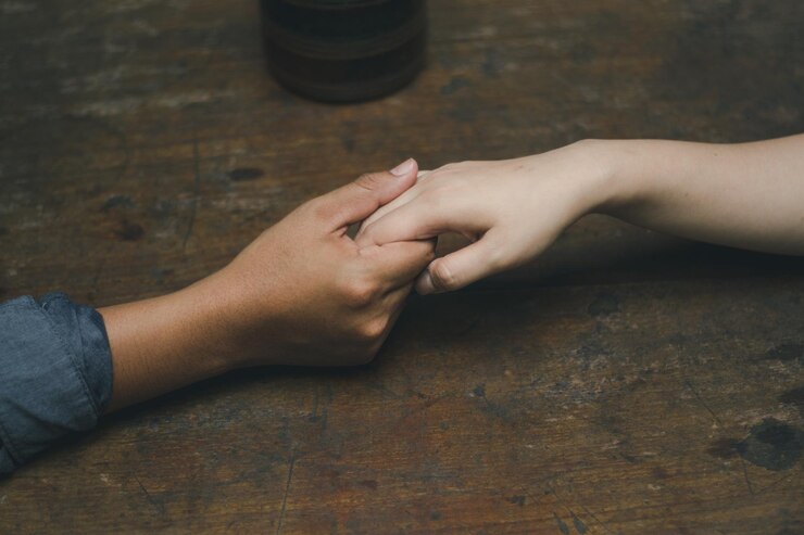 Fotografie cropped image of couple holding hands on wooden table