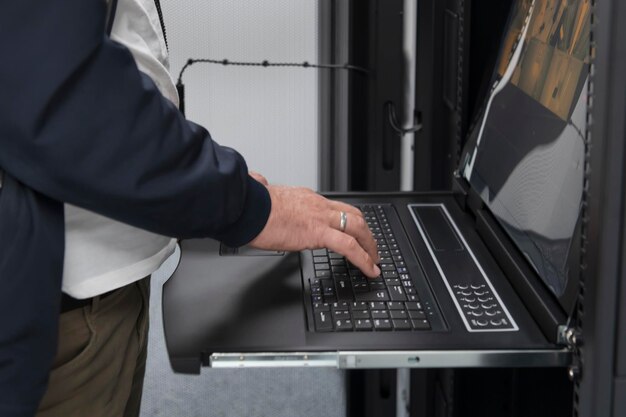 Detailní záběr rukou datového centra Engineer používá klávesnici na superpočítači. Specializované zařízení serverové místnosti s mužským správcem systému, který pracuje s datovou ochranou sítě pro kybernetickou bezpečnost.