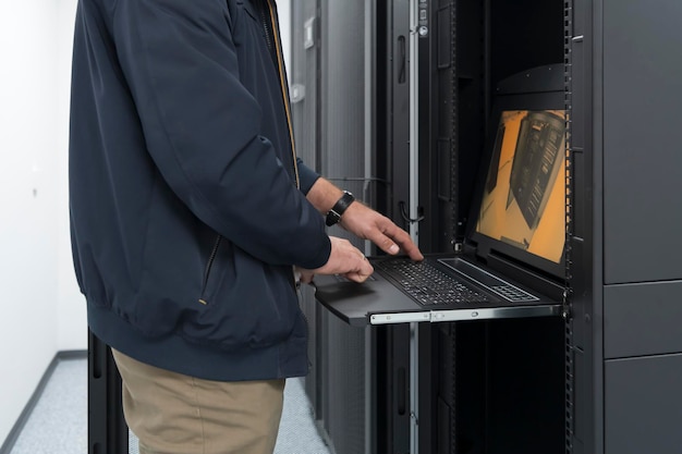 Detailní záběr rukou datového centra Engineer používá klávesnici na superpočítači. Specializované zařízení serverové místnosti s mužským správcem systému, který pracuje s datovou ochranou sítě pro kybernetickou bezpečnost.