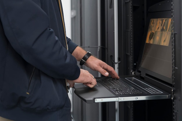 Detailní záběr rukou datového centra Engineer používá klávesnici na superpočítači. Specializované zařízení serverové místnosti s mužským správcem systému, který pracuje s datovou ochranou sítě pro kybernetickou bezpečnost.