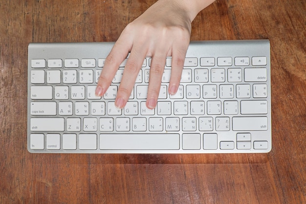 Directly above shot of person holding keyboard over desk