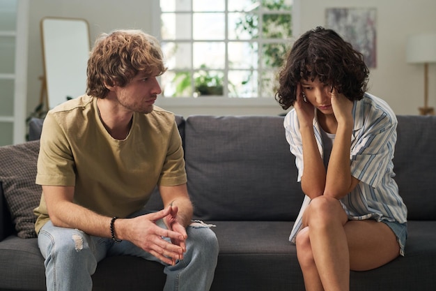 displeased young man looking at his stressed wife touching her head