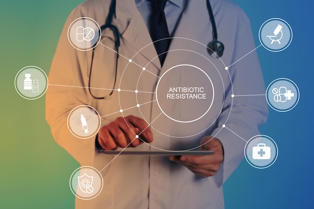 Doctor with modern tablet on color background closeup Concept of antibiotic resistance