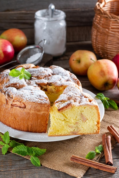 Domácí kulatý piškotový dort nebo šifonový dort s jablky na bílém talíři, tak měkký a lahodný s ingrediencemi: vejce, mouka, mléko na stole. Domácí pekařský koncept pro pozadí a tapetu.