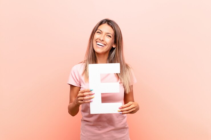 Fotografie excited, happy, joyful, holding the letter e of the alphabet to form a word or a sentence.