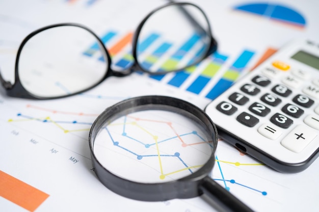 Eyeglass with calculator on chart graph paper Finance account statistic investment data economy stock exchange business