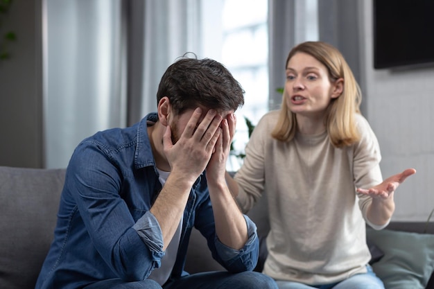 family quarrel woman quarrels and yells at the loser's husband couple at home sitting in the living room on the couch