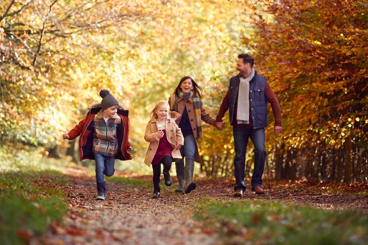 Fotografie family walking along track in autumn countryside with children running ahead