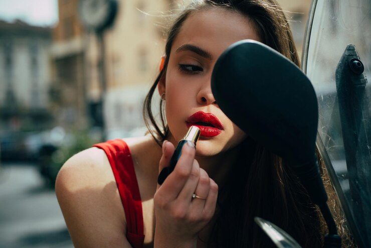 Fotografie fashion girl with red lips put lipstick looking in a rear street fashion city life makeup in motion