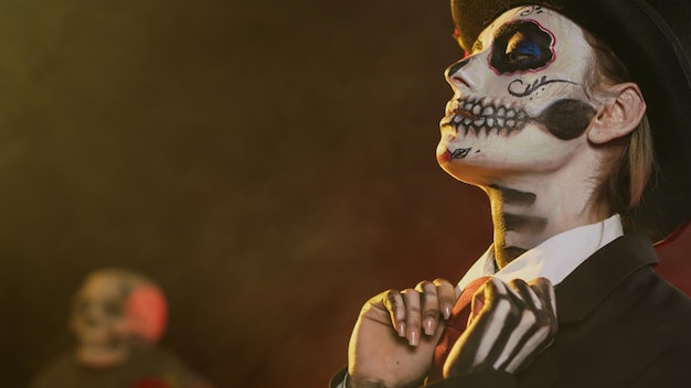 female adult in halloween costume with skull body art celebrating holy mexican tradition, posing in studio. looking like lady of death at santa muerte ritual celebration. handheld shot.