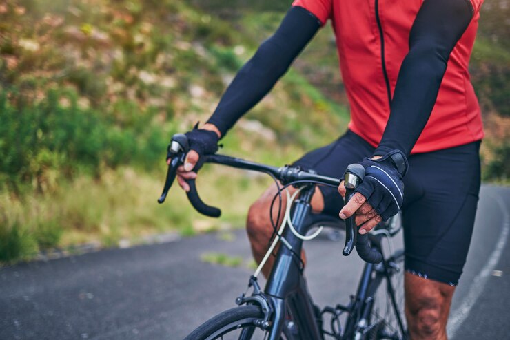 Fotografie fitness cycling and hands with person on bike in nature for sports training or challenge exercise workout and health with closeup of man on bicycle in mountains for energy freedom or performance