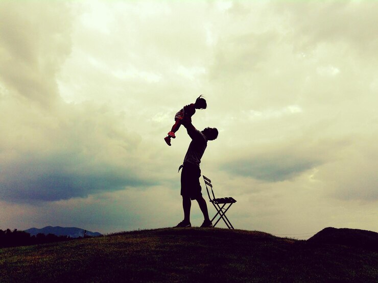 Fotografie full length of father holding daughter on field against cloudy sky