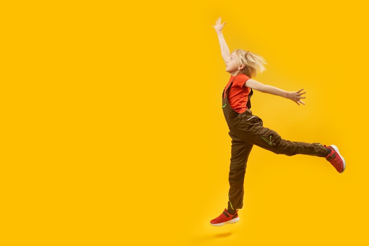 Fotografie fulllength side view portrait of bouncing boy on yellow background child jumps happily copy space