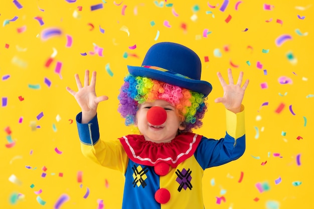 funny kid clown against yellow wall.