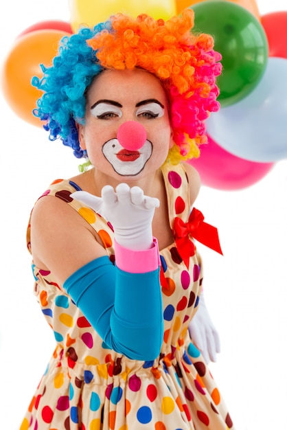 funny playful female clown in colorful wig air kissing.