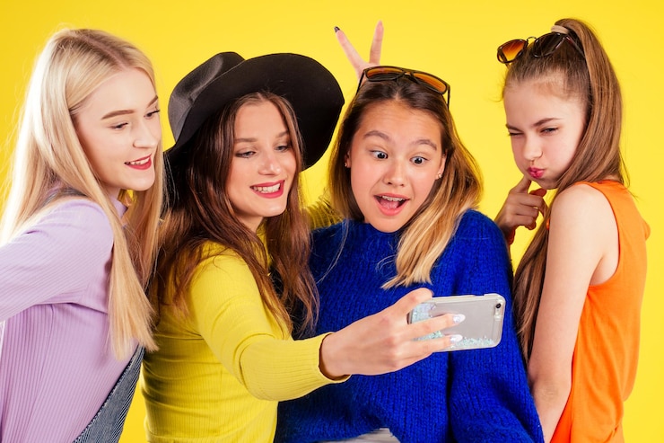 Fotografie group of four laughing girls having party summer style yellow background studio