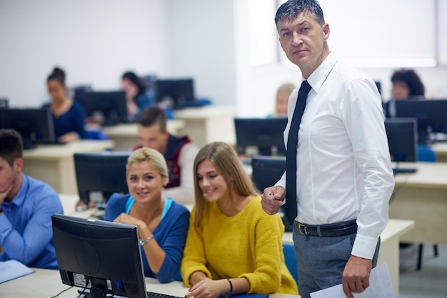 group of students with teacher in computer lab classrom learrning lessons get help and support
