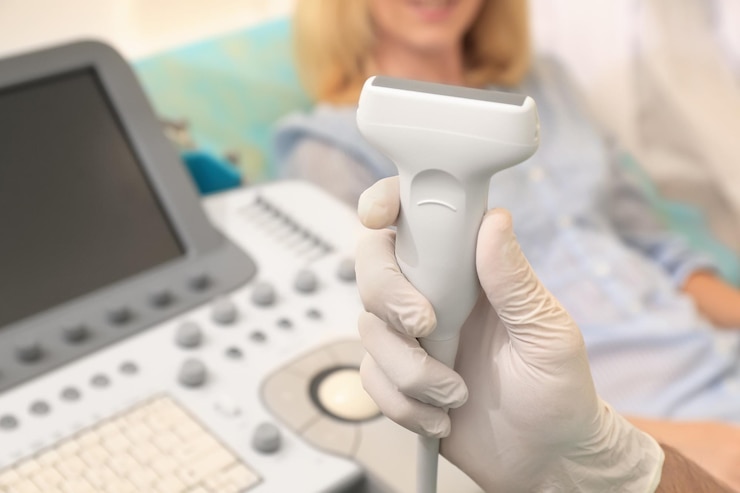 Fotografie hand of doctor with ultrasound equipment and blurred patient on background