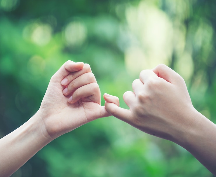 Fotografie hands hook each other's little finger on nature background