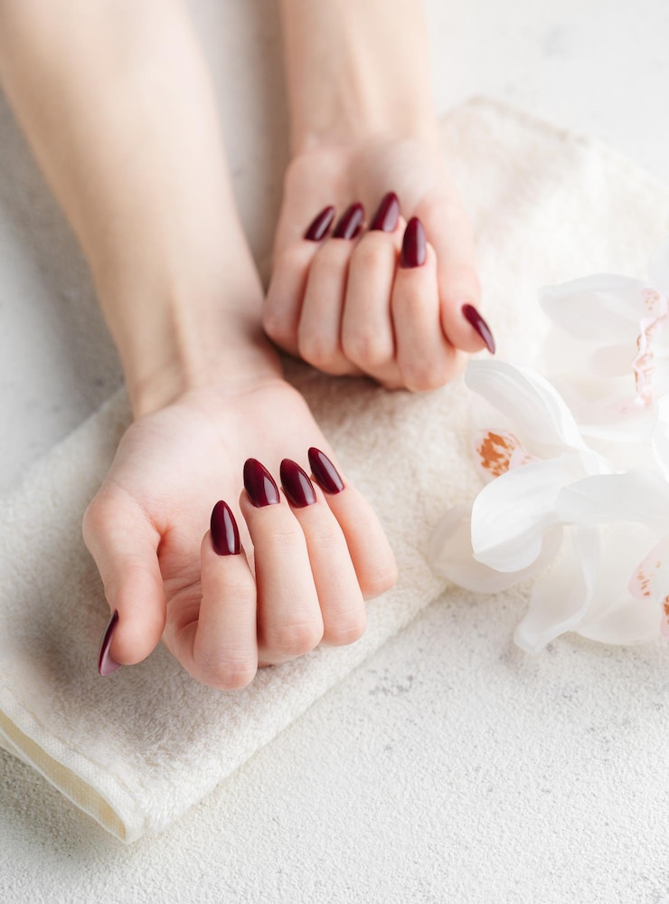Fotografie hands of a young woman with dark red manicure on nails
