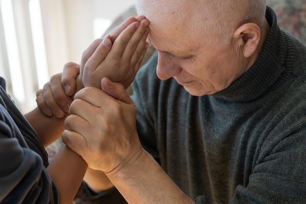 hands of grandfather and granddaughter with prayer.