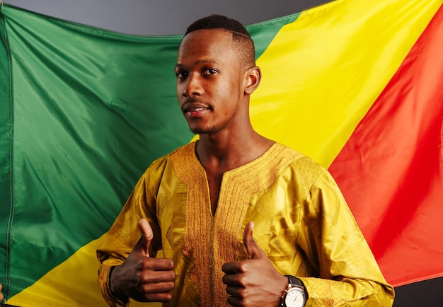 happiness african man in traditional clothes dancing with flag of congo isolated on gray background