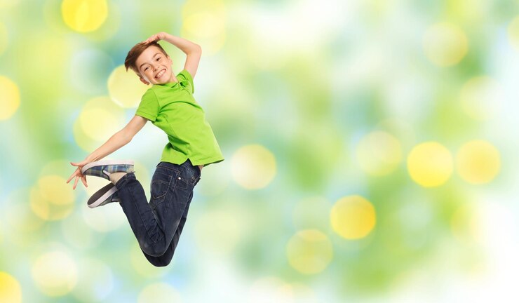 Fotografie happiness, childhood, freedom, movement and people concept - smiling boy jumping in air over summer green holidays lights background