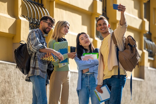 Happy cheerful students making group selfie in university campus