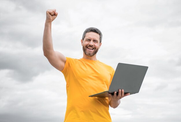 happy man working online on laptop on sky background