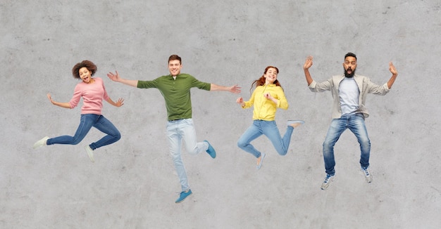 happy people or friends jumping in air over gray
