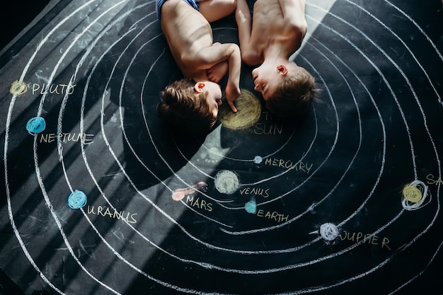 high angle view of shirtless siblings lying on chalk drawing