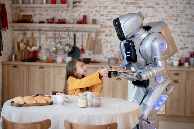 house robot offering meatballs to the smiling girl at the table