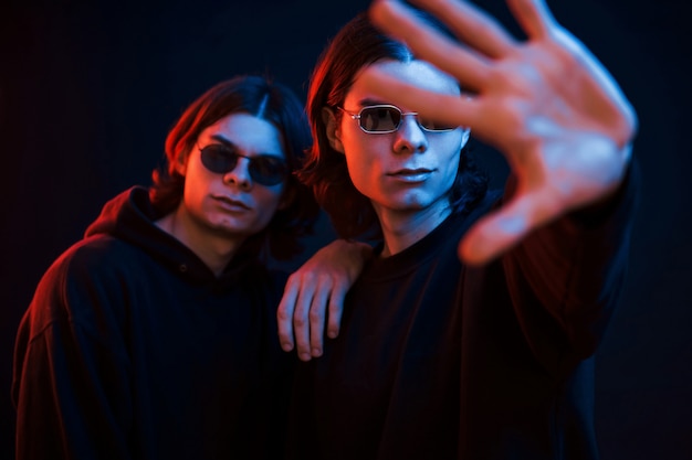i will protect you. portrait of twin brothers. studio shot in dark studio with neon light