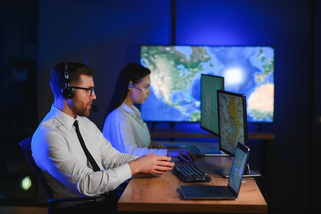 In Monitoring Room Technical Support Specialist Speaks into Headset His Colleagues are Working in the Background