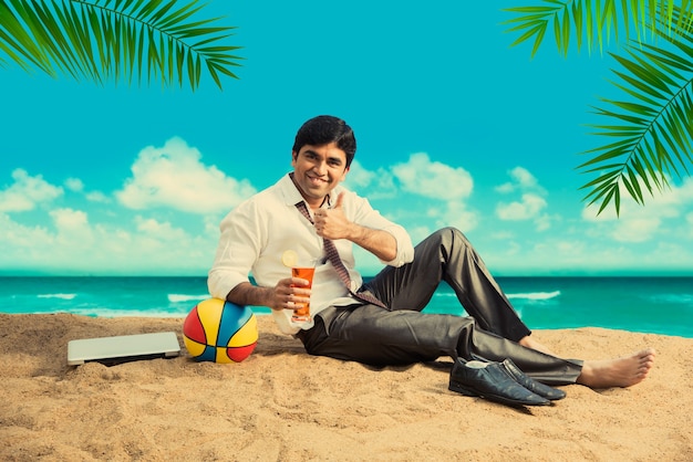indian asian young businessman relaxing or working from beach enjoying break from work