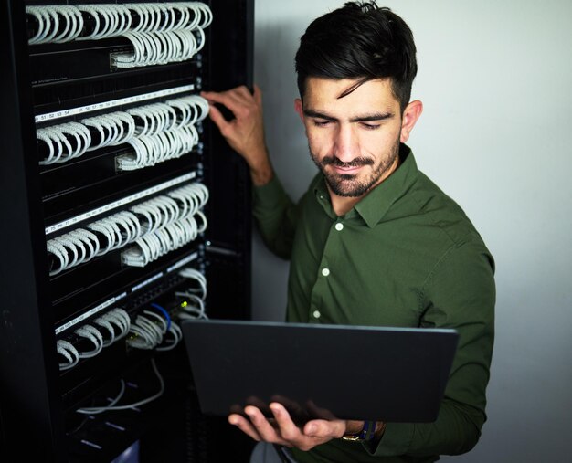 laptop data center and male technician in a server room for technical repairs by a control box technology engineering and professional man electrician working on computer for cybersecurity system
