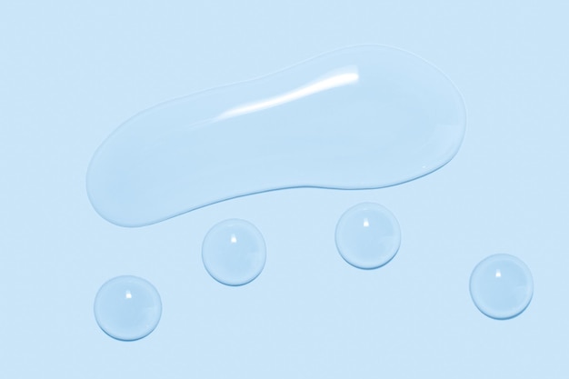 Large drops of transparent Gel liquid water on a blue background top view closeup