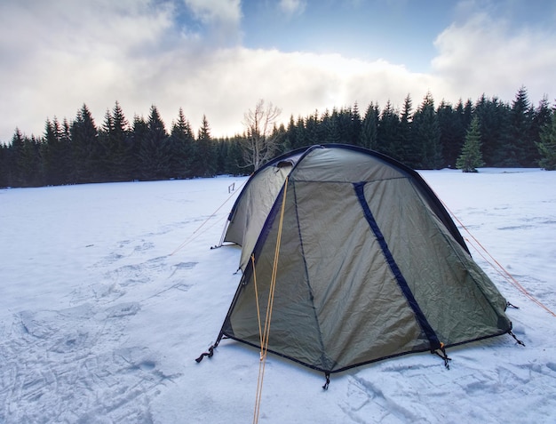 light green tent in extreme winter conditions landscape covered with snow high in the mountains