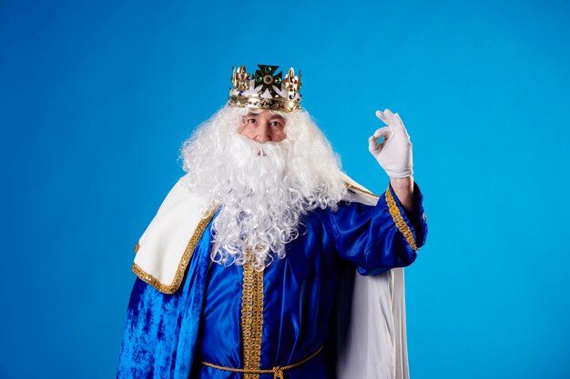 Magician King making the Ok gesture on a blue background