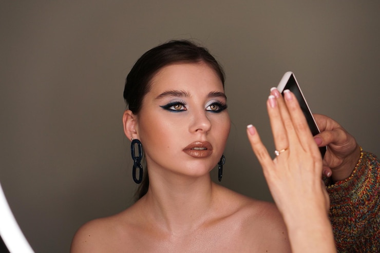 Fotografie make up artist taking mobile photo for the model with blue fashion makeup